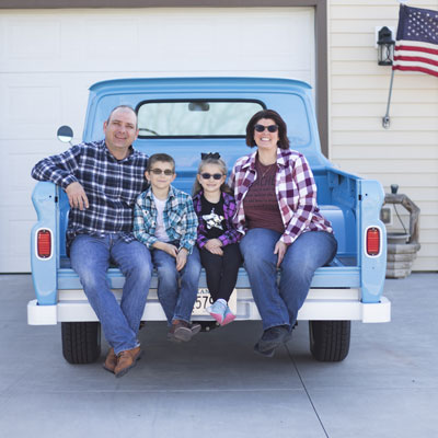 A family of four sitting in a pick-up truck bed