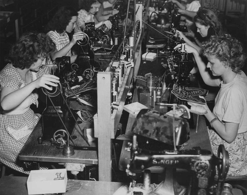 Workers sewing designs into sections of boots